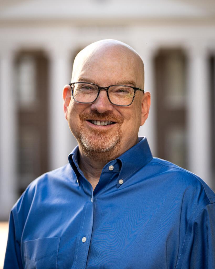 Charlie Poag smiles for a headshot in front of Davidson Hall